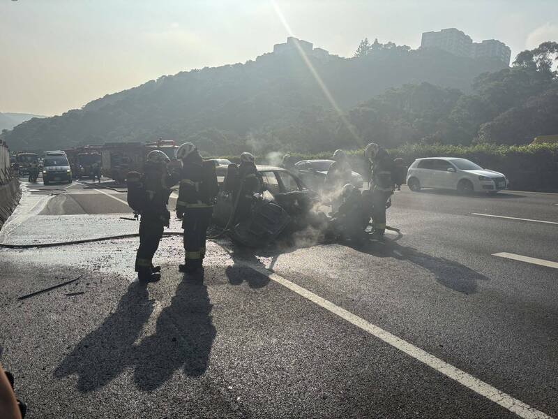 中山高南下林口今天上午七时卅分传出火烧车，驾驶与乘客两人仓皇逃生，幸无大碍，这起车祸造成中山高双向都回堵10余公里，车潮消化中；图为消防员残火处理。（记者吴仁捷翻摄）