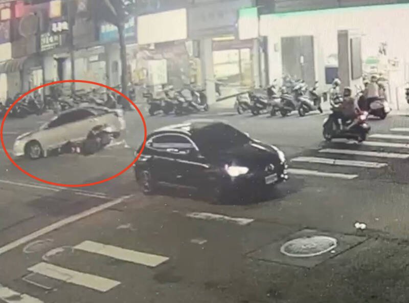 银色轿车从外侧车道「鬼切」左转，直行机车骑士闪避不及，从后方撞上，连人带车被卷进车底。（记者蔡淑媛翻摄）