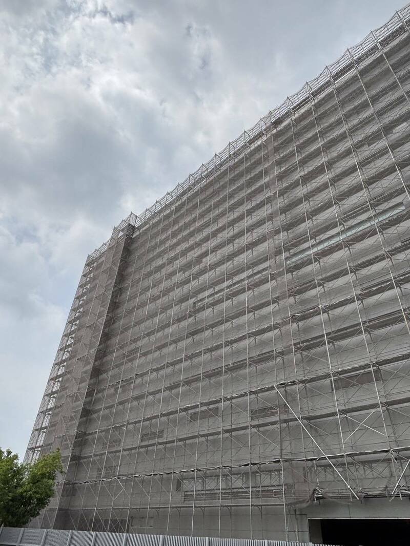 高雄市立殡仪馆附近1栋民间殡葬业者的大楼工地，遭控有工人在高空鹰架作业时未做安全带防护。（高雄市劳工局提供）