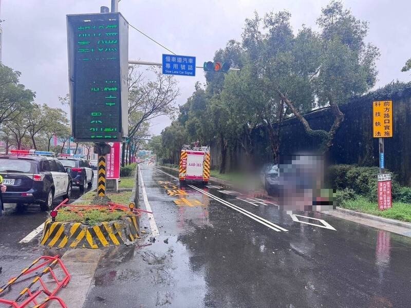 多元计程车打滑冲撞分隔岛，女乘客抛出车外倒卧血泊，警消人员到场抢救与处理。（记者邱俊福翻摄）