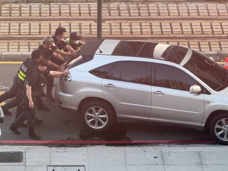 高雄轿车不明原因撞断轻轨号志，警察协助把肇事车推离道路上，避免影响交通。（民众提供）
