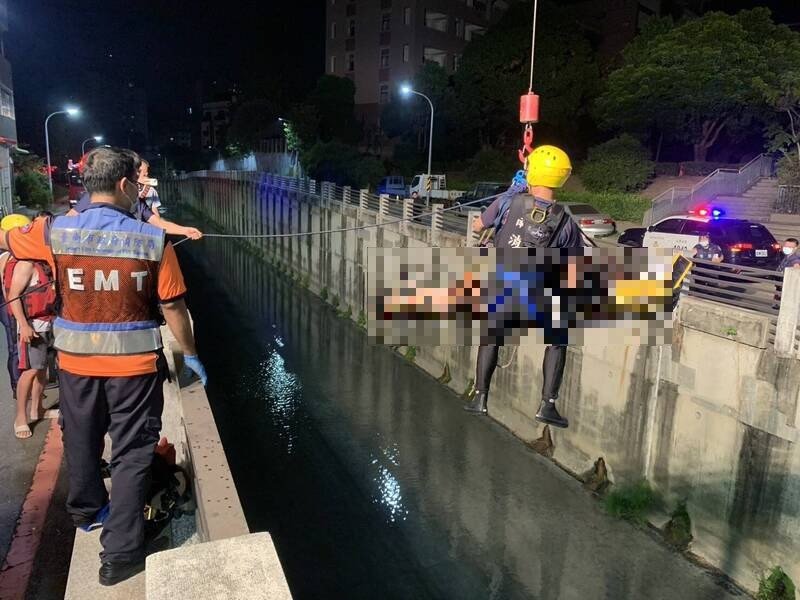 消防人员将坠落台南北区柴头港溪的受伤女子吊挂上岸送医。（民众提供）