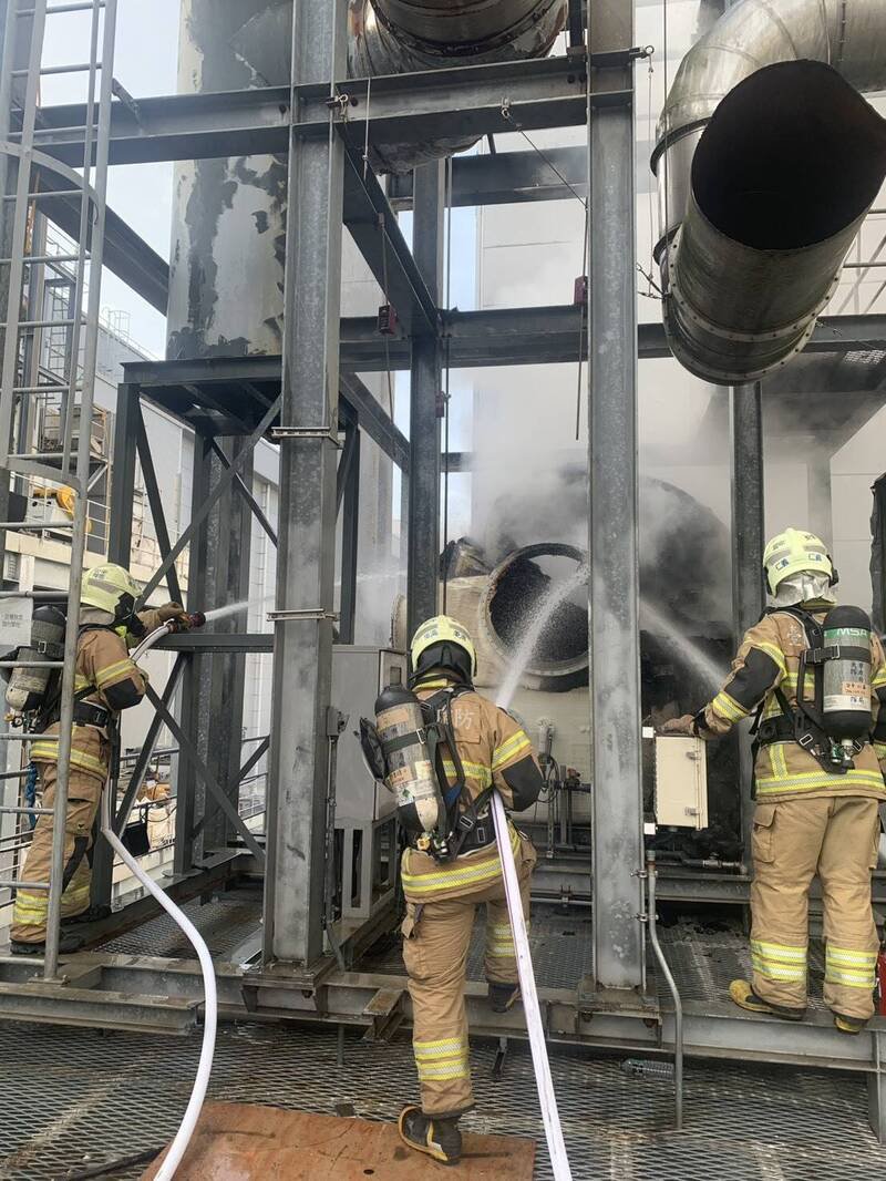 消防人员近距离朝工厂外部滤材射水降温，穿戴完整防护装备进行抢救，确认燃烧物无危害性，并防止火势延烧至内部产线。（民众提供）