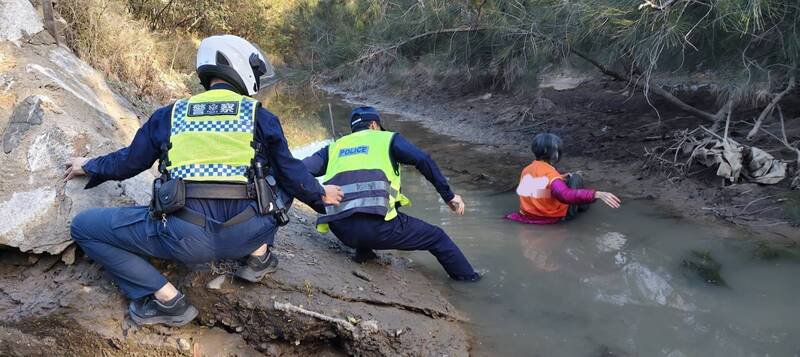 金门县警局金湖分局员警冲下出海口排水沟抢救身陷泥滩妇人。（金湖分局提供）