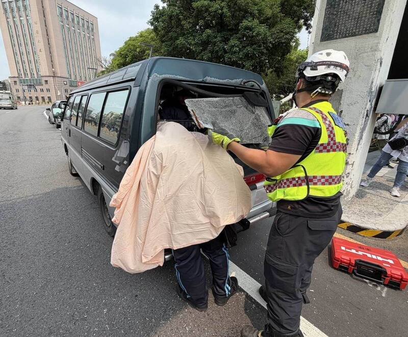 单车男撞厢型车头卡挡风玻璃被迫站著，消防员拆玻璃抢救。（消防局提供）