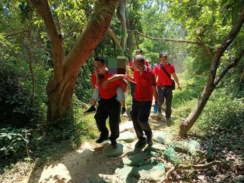 女山友出现胸闷等症状无法行走，消防员背负救援下山。（嘉义市消防局提供）